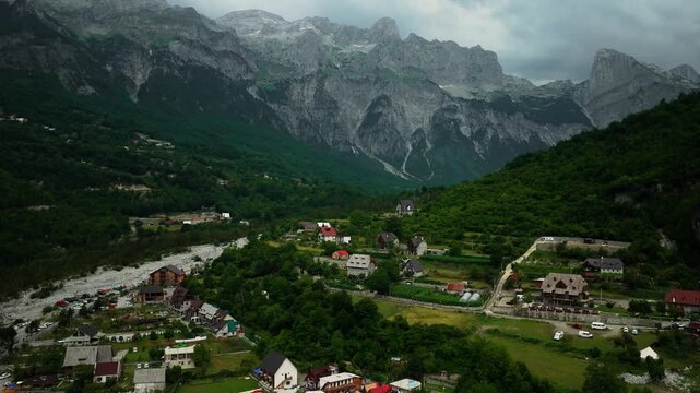 Aerial pull away over Theth village beneath jagged Albanian peaks