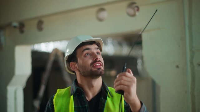 Caucasian foreman man controlling construction process walkie talkie male supervisor speaking radio looking at roof contractor guy coordinating workers civil engineer technician directing operations