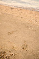 Obraz premium Footprints on a sandy shoreline in Kvarner Bay, Croatia. Concept of travel, summer vacations, freedom, and taking steps forward.