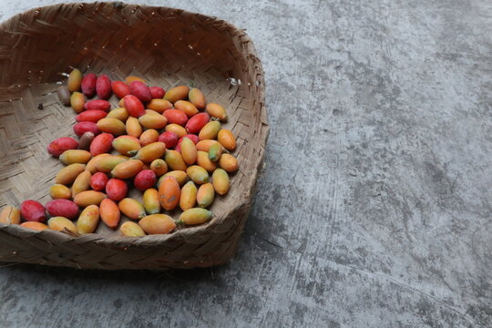 Fresh melinjo fruits (Gnetum gnemon) collected in a woven bamboo basket after harvest in rural Java, Indonesia. Traditional agriculture and local food ingredient concept.
