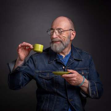 Head and shoulders portrait of bald and bearded senior man enjoying a cup of coffee