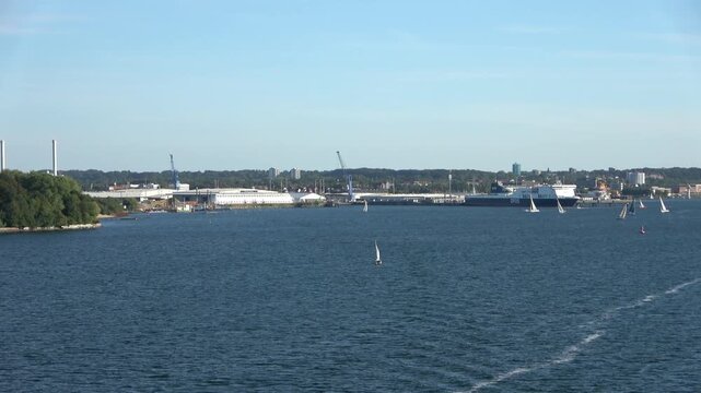 Panoramic view of the port of Kiel in Germany, with sailboats and a large ferry in the background