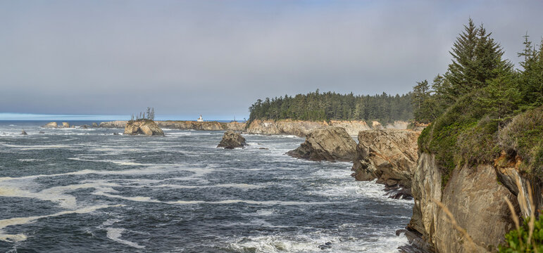 Beautiful scenic view of a historic lighthouse on a rocky ocean coast with forested cliffs