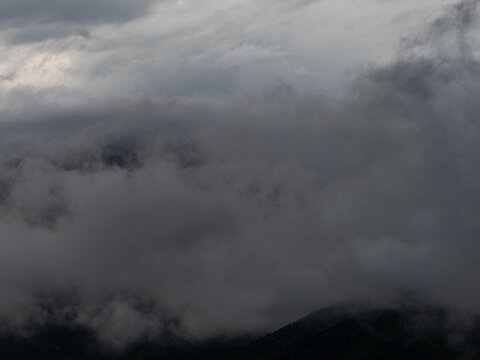 Heavy gray storm clouds and fog over dark hills, abstract gloomy sky background