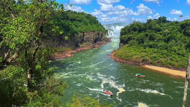 Scenic view of Iguazu Falls in Argentina with lush green jungle and tourist boats on the river