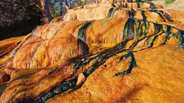 Sunrise glows across the vibrant thermal water and travertine edges of the mineral pool at Pinkerton Hot Springs in Colorado