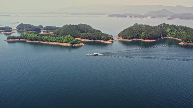 Aerial View of Boat Sailing Through Lake with Forested Islands in Zhejiang, China in Qiandao Lake, Zhejiang, China