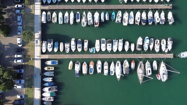 Top-down aerial view of Punat Marina on Krk Island, Croatia, showing rows of boats and yachts moored along floating piers in the clear Adriatic waters.