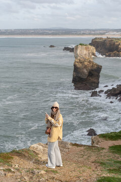 Woman using smartphone on rocky Atlantic coast