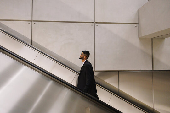Young businessman riding escalator seeing future success