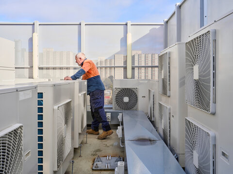 Refrigeration Mechanic Checks Air Conditioning Units on a Rooftop