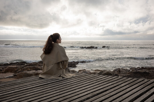 Woman sitting alone by the Atlantic Ocean