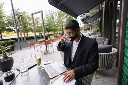 Young businessman working remotely at outdoor cafe in city
