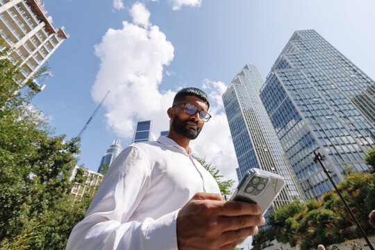 Young businessman using smartphone in city connecting to technology