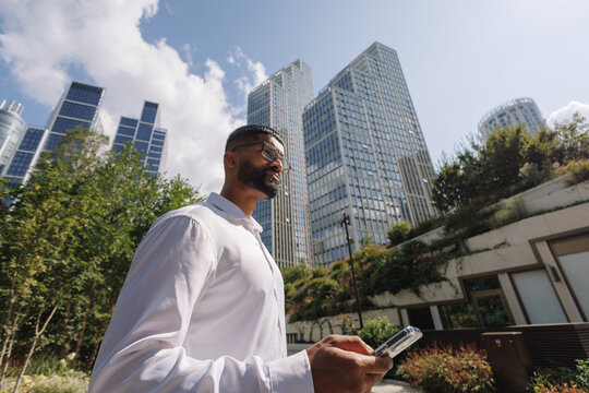 Young businessman walking in modern city checking phone