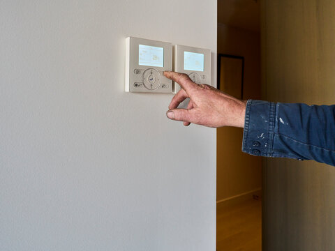 Aircon Technician Adjusting a Thermostat in a Room