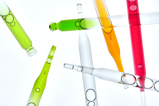 Laboratory Glass Pipettes with Colorful Liquids on Light Background.