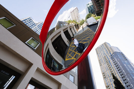 Young business man reflecting in city traffic mirror