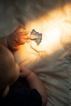Baby Reaching for Pacifier in Sunlight