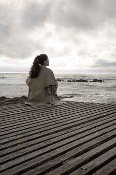 Woman contemplating the ocean under cloudy sky