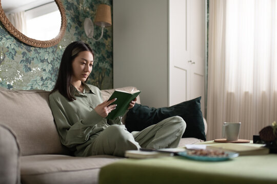Asian woman reading book at home