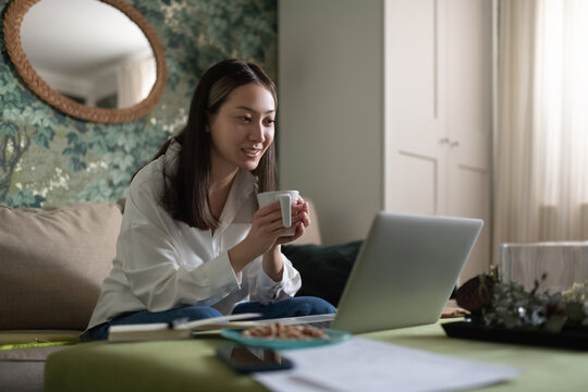 Cheerful Asian female speaking with online friends at home