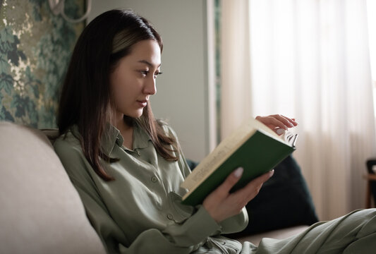Young Asian female reading book at home