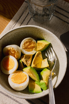 Eggs and avocado served in a bowl on a wooden table