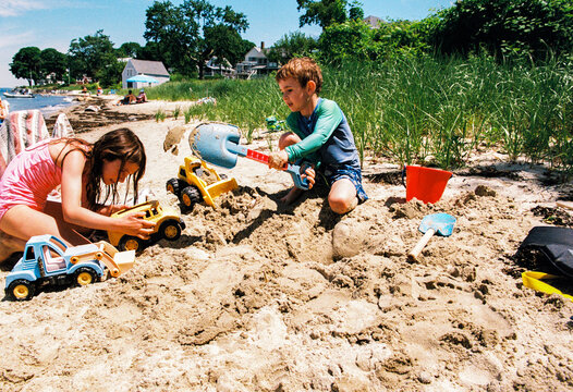 Two children play together on a beach in Maine