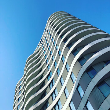 Low angle view of a curvy modern high rise building against a clear blue sky, London, England, UK