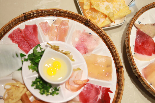 Close-up of four platters with ingredients for traditional Yunnan Crossing-the-Bridge Rice Noodles (Guoqiao Mixian)