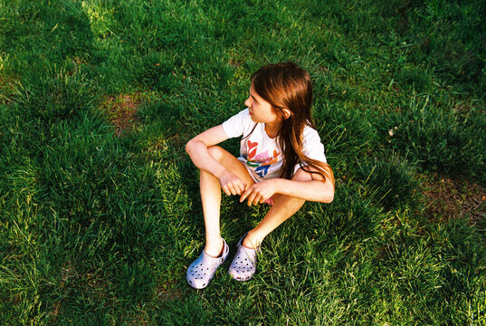 Girl sits alone in the grass on a summer evening