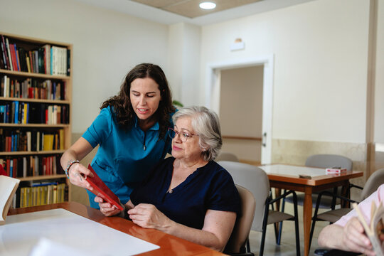 Caregiver assisting senior woman with activity in library