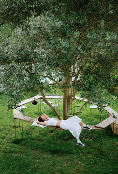 Chinese woman resting on a circular bench beneath a large tree