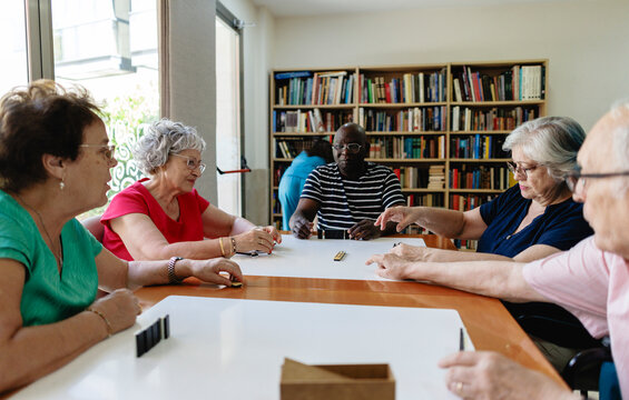 Diverse seniors playing dominoes together at community center