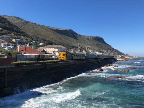 Southern Line coastal commuter train travelling along the waterfront sea wall, Kalk Bay, Cape Town, Western Cape, South Africa