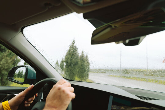 View of crossroads from the windshield, hands on steering wheel