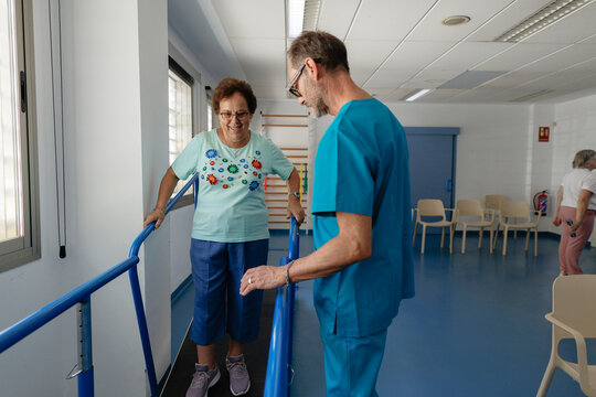 Physiotherapist assisting senior woman with walking rehabilitation