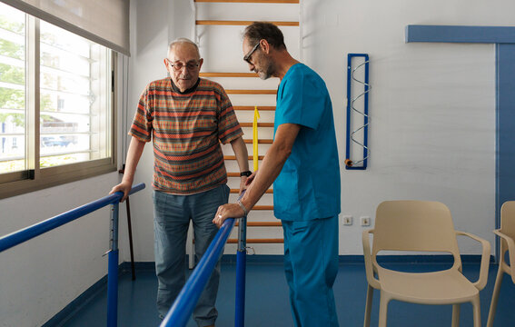 Elder man doing physical therapy with physiotherapist