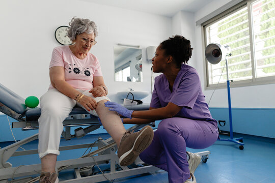 Healthcare professional examining senior woman's painful knee