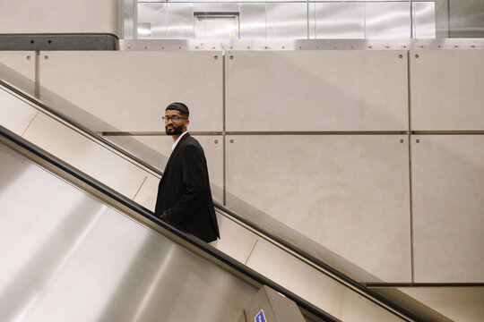 Young businessman ascending subway escalator in urban city