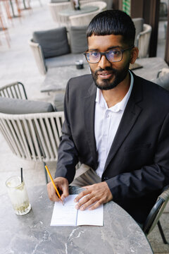 Young businessman writing notes at outdoor cafe