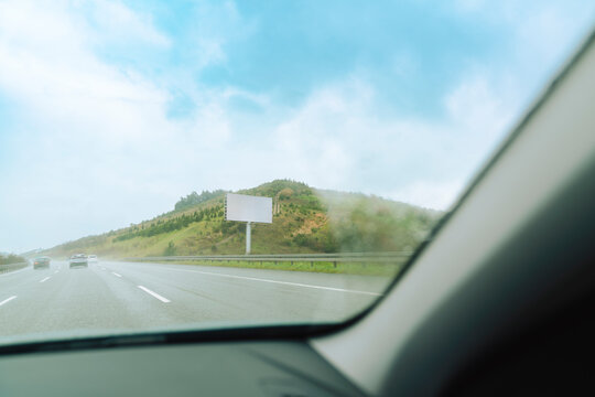 View of blank billboard on the side of highway from car interior