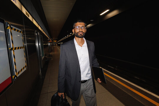 Young businessman waiting on subway platform commuting to work