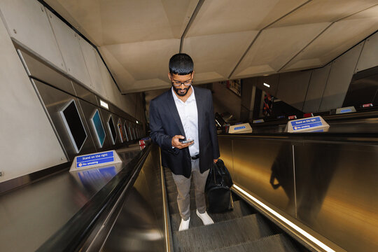 Young businessman commuting in city subway escalator