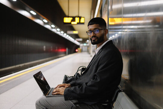 Young businessman working on laptop at subway station