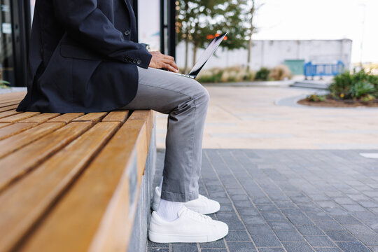 Business man working on laptop sitting on bench outdoors