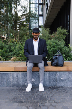 Young man working on laptop outdoors on bench