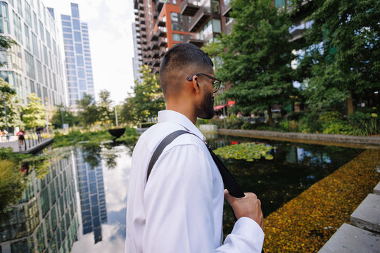 Young businessman walking past a city pond