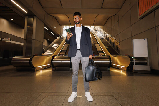 Young businessman checking smartphone at subway station